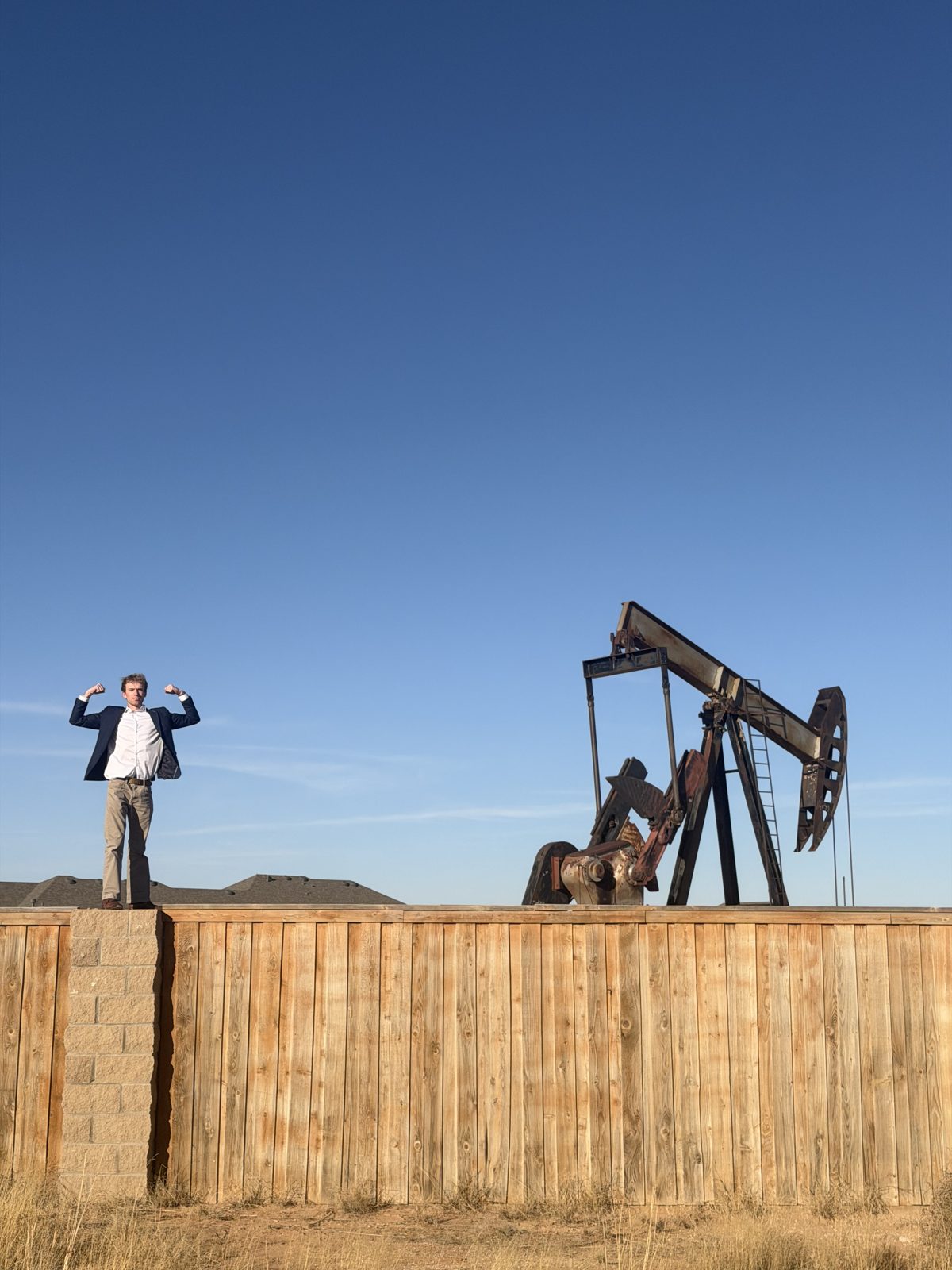 Aidan Isaac standing in front of a pump jack in Texas oil country